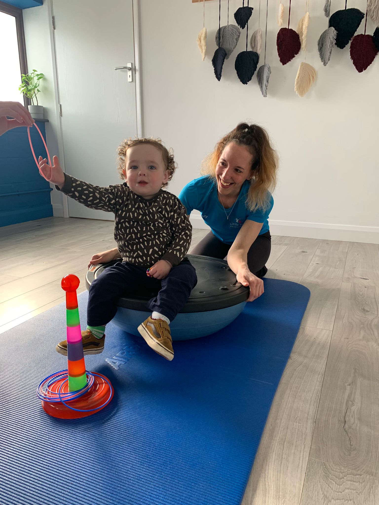 Paediatric physio in Sandy — child physiotherapist supporting a toddler on a balance disc during a developmental session